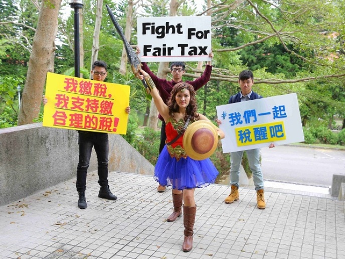 新竹地區大學校園首場論壇「法稅新知 你我他」請來神力女超人，手拿象徵正義的劍和盾，呼籲「我們一起『稅』醒」、「支持繳合理的稅」。